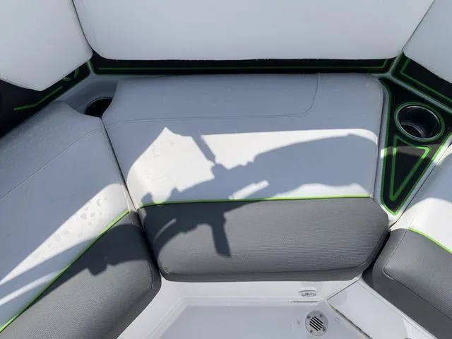 Slide: The Image of 2024 Tahoe 210 S boat interior with gray and white seating, green accents, and cup holder. - 23