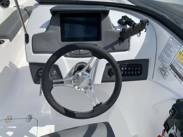 Slide: The Image of 2024 Tahoe 210 S boat dashboard with steering wheel and control panel. - 35