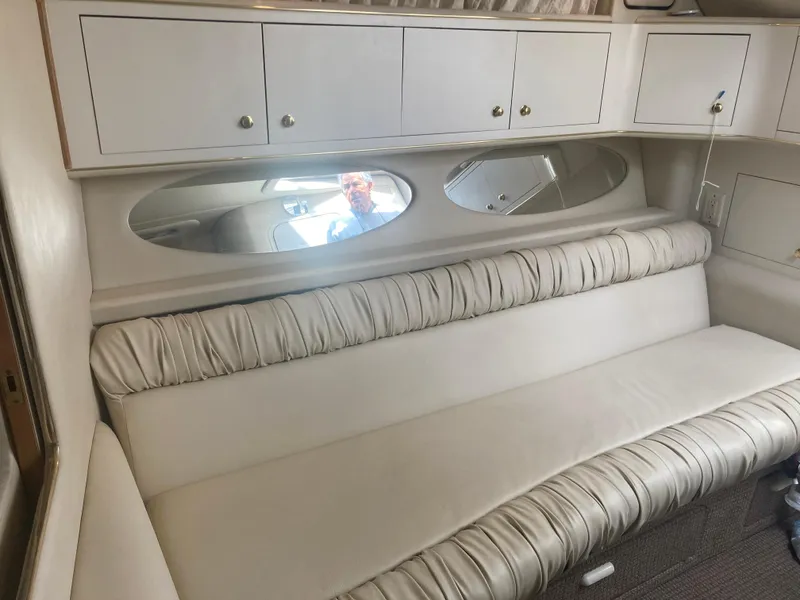 Slide: The Image of Interior of 1999 Sea Ray 330 Express Cruiser with white seating and storage cabinets. - 16