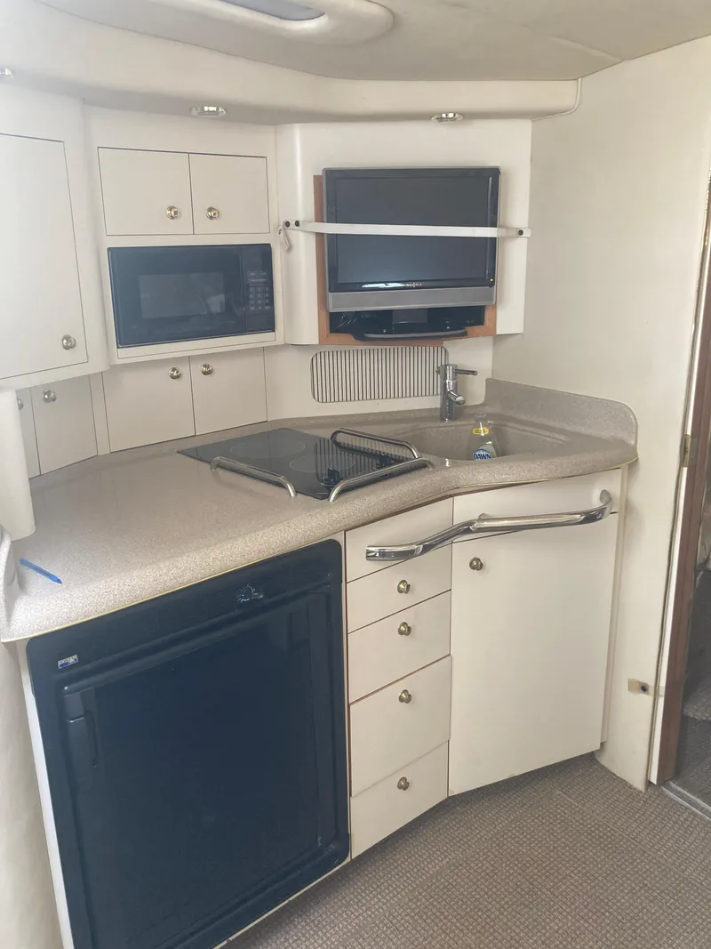 Slide: The Image of 1999 Sea Ray 330 Express Cruiser kitchen with appliances and storage cabinets. - 17