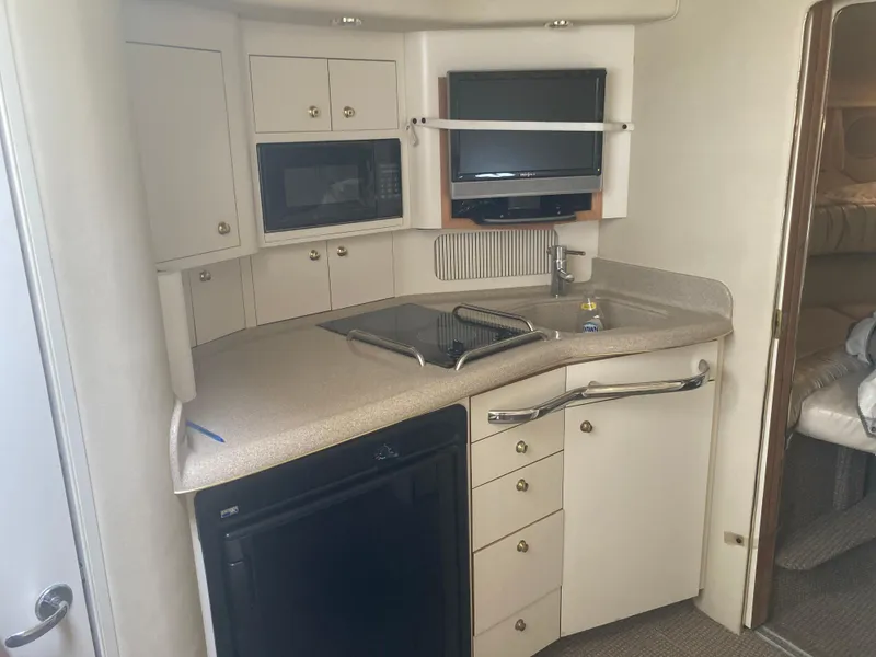 Slide: The Image of 1999 Sea Ray 330 Express Cruiser kitchen with appliances and storage cabinets. - 19