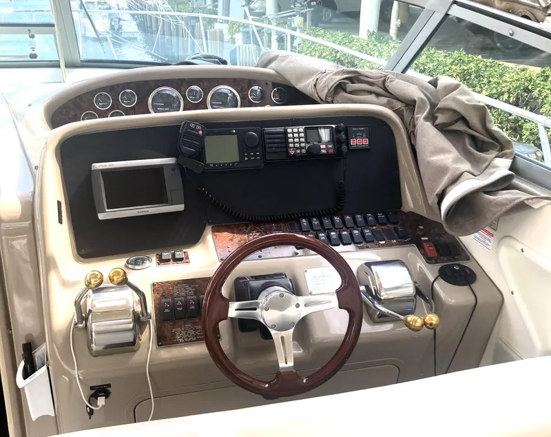 Slide: The Image of 1999 Sea Ray 330 Express Cruiser helm with steering wheel and navigation controls. - 38