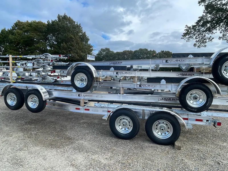 Slide: The Image of 2025 Load Rite 5s-AC23T5200 trailers stacked outdoors on gravel lot. - 5