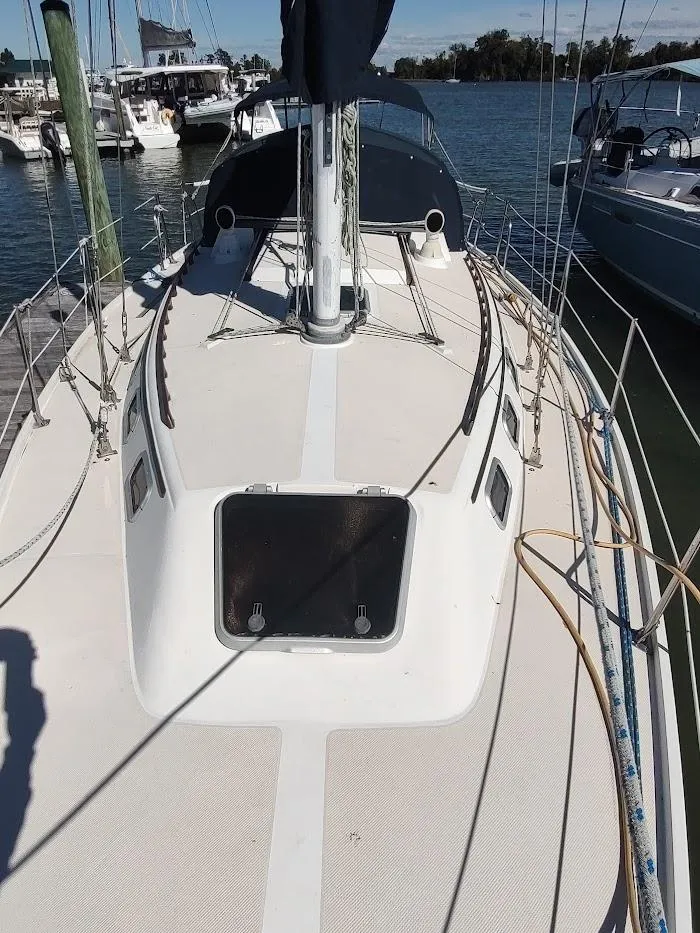 Slide: The Image of 1990 Catalina C-34 sailboat deck view at marina, featuring mast and hatch. - 10