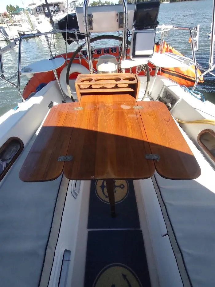 Slide: The Image of 1990 Catalina C-34 sailboat cockpit with wooden table and steering wheel, docked at marina. - 29
