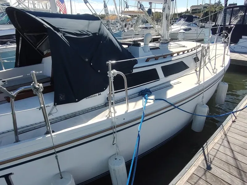 Slide: The Image of 1990 Catalina C-34 sailboat docked at marina with blue cover and fenders. - 4
