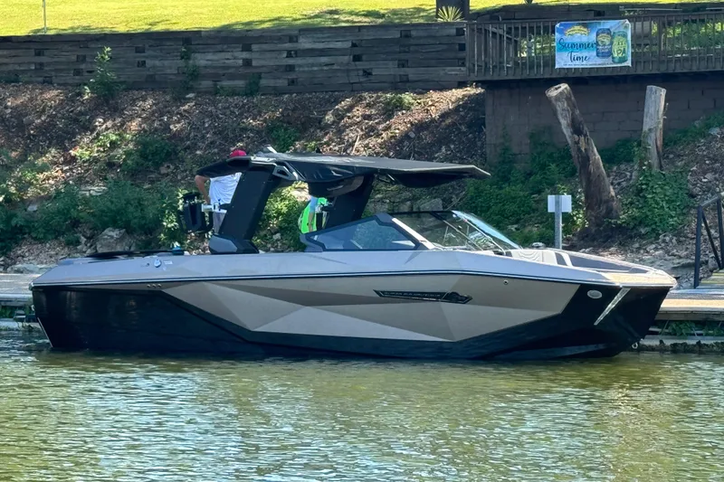 Slide: The Image of 2025 Nautique Super Air Nautique G23 boat docked on a calm lake. - 0