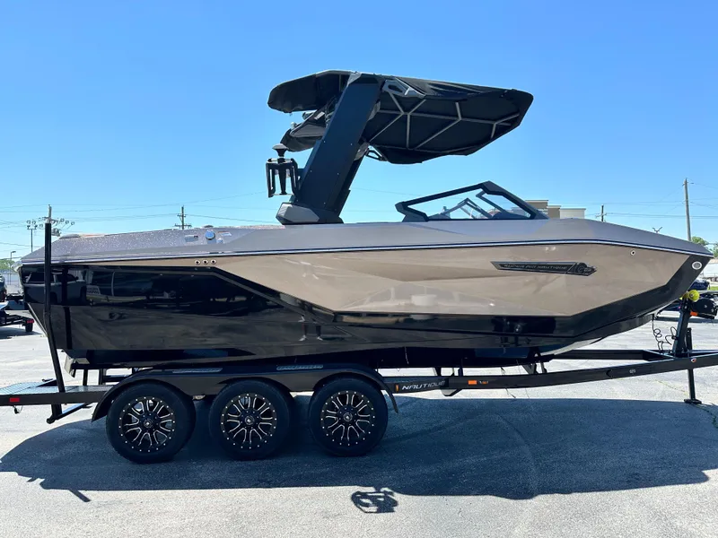 Slide: The Image of 2025 Nautique Super Air Nautique G23 boat on trailer, sleek design, black and gray finish. - 4