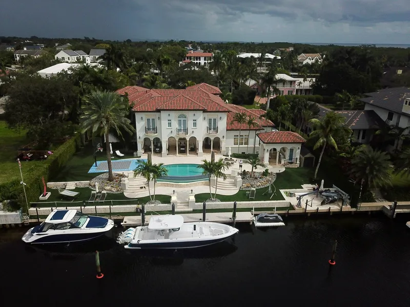 Slide: The Image of Luxurious waterfront mansion with 2022 Intrepid 407 Panacea boat docked nearby. - 1