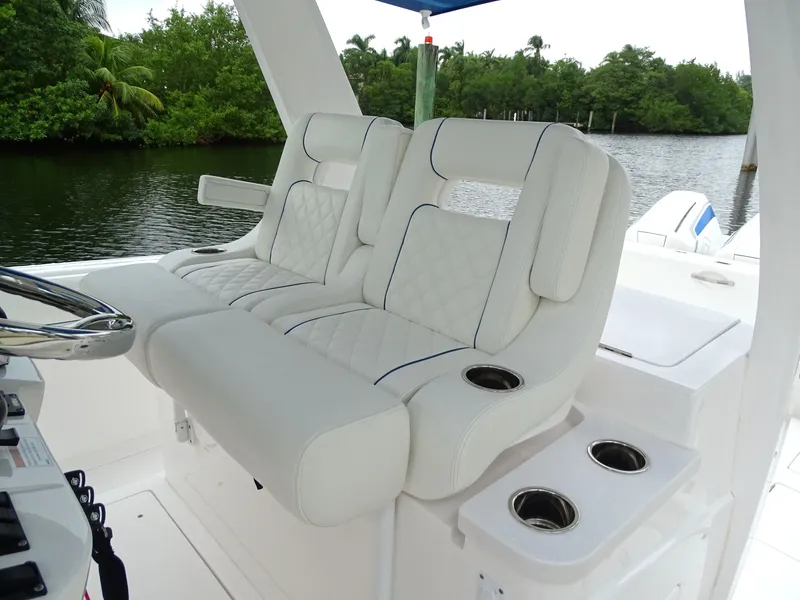 Slide: The Image of Luxurious seating on 2022 Intrepid 407 Panacea boat with cup holders, near lush greenery. - 26