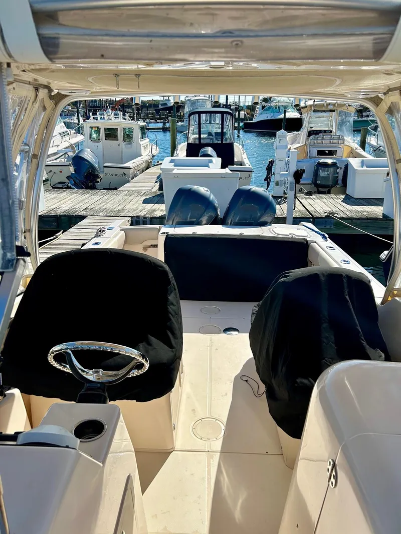 Slide: The Image of 2012 Grady-White Freedom 285 boat interior at marina, featuring dual engines and covered seats. - 25