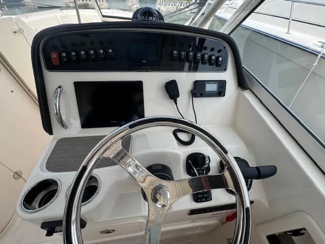 Slide: The Image of 2023 Grady-White Freedom 307 boat dashboard with steering wheel and control panel. - 7
