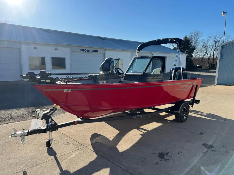 Slide: The Image of 2025 Lund 1775 Adventure Sport boat in red, parked outside a showroom. - 2