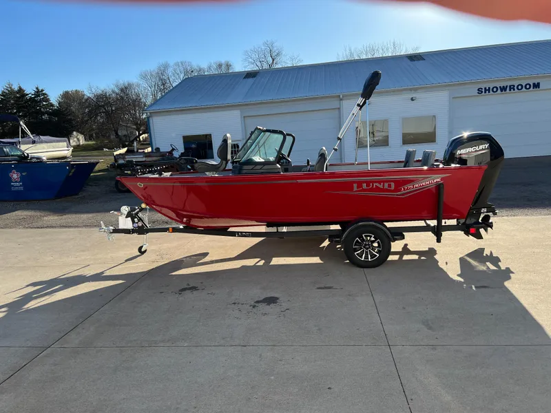 Slide: The Image of 2025 Lund 1775 Adventure Sport boat in red, parked outside a showroom. - 3