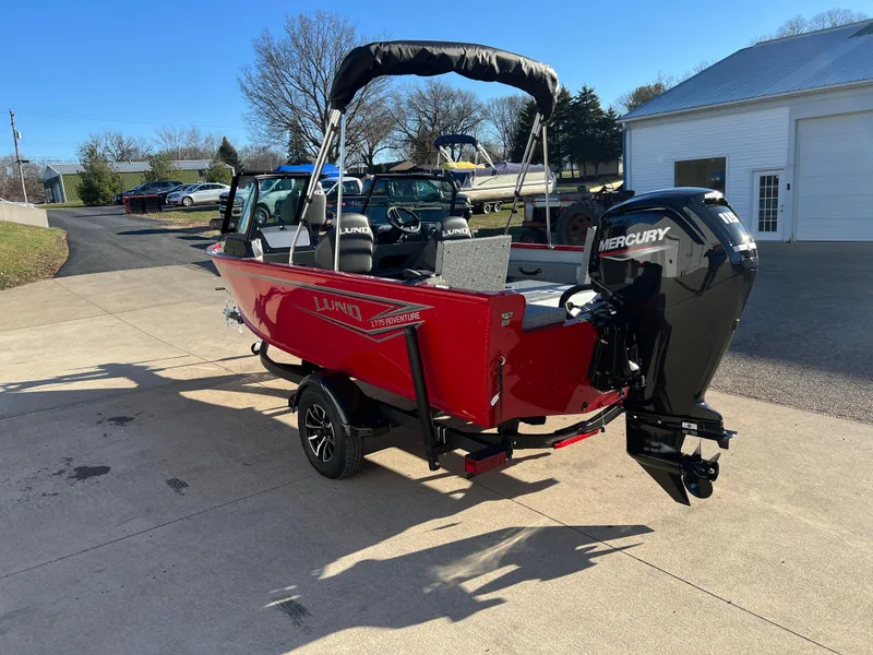 Slide: The Image of 2025 Lund 1775 Adventure Sport boat with Mercury outboard motor, parked outdoors. - 4