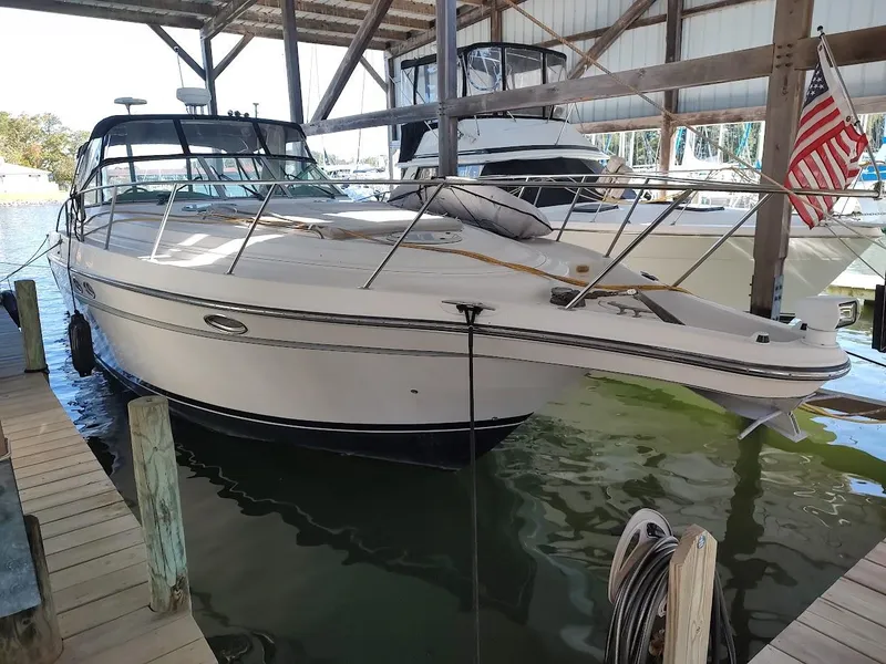 The Image of 1999 Maxum 4100 SCR yacht docked in a covered marina, displaying sleek design. - 0