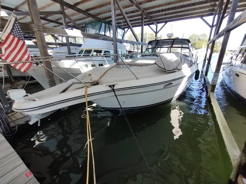 Slide: The Image of 1999 Maxum 4100 SCR yacht docked under a covered marina with American flag. - 1