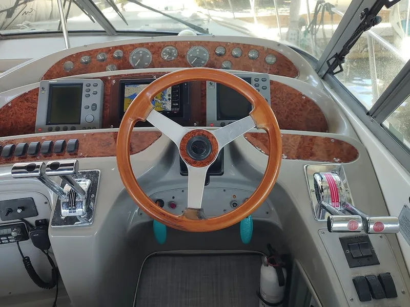 Slide: The Image of 1999 Maxum 4100 SCR boat dashboard with wood steering wheel and navigation instruments. - 13