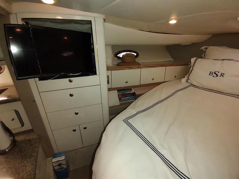 Slide: The Image of 1999 Maxum 4100 SCR cabin interior with bed, TV, and storage cabinets. - 38