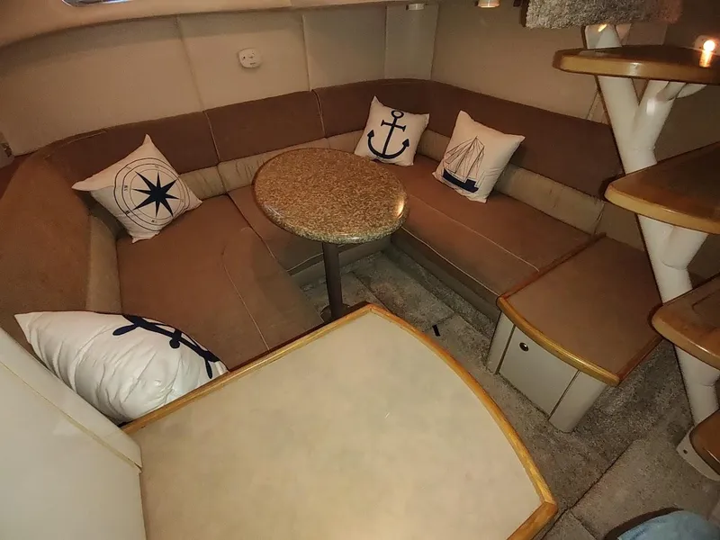 Slide: The Image of Interior of 1999 Maxum 4100 SCR yacht with cozy seating and nautical-themed pillows. - 48