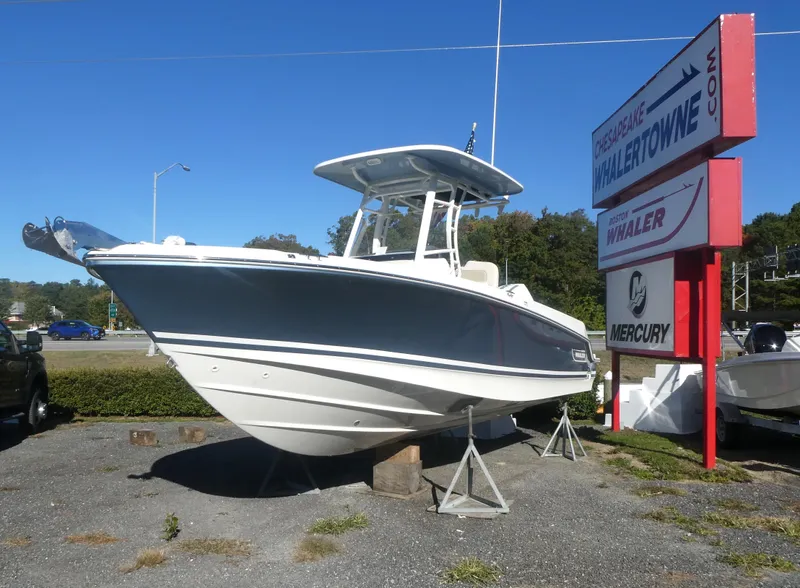 The Image of 2025 Boston Whaler 230 Outrage boat displayed outdoors near dealership sign. - 0