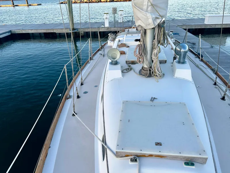 Slide: The Image of 1970 Hinckley 38 sailboat docked, showcasing deck and mast in a serene marina setting. - 13