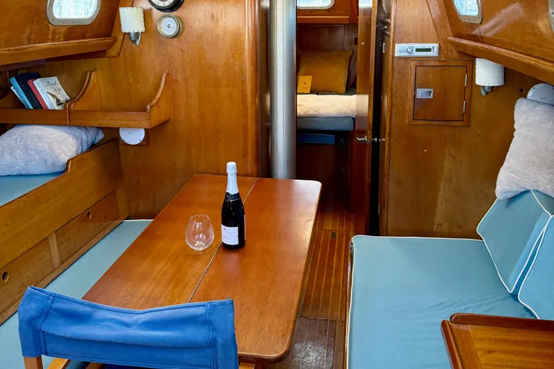 Slide: The Image of Interior of a 1970 Hinckley 38 sailboat with wooden furnishings and a cozy dining area. - 2