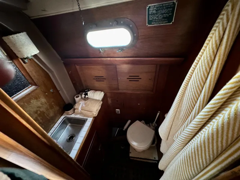 Slide: The Image of 1970 Hinckley 38 yacht bathroom with sink, toilet, and porthole window. - 20