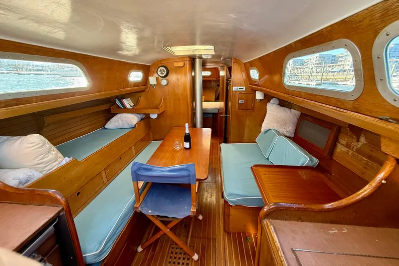 Slide: The Image of 1970 Hinckley 38 sailboat interior with wooden furnishings and cozy seating area. - 22