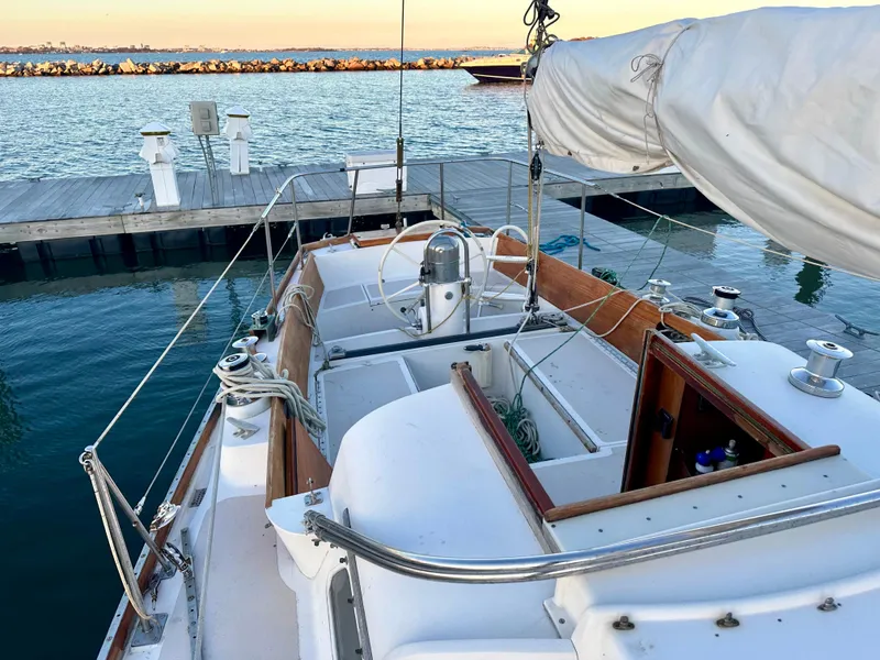 Slide: The Image of 1970 Hinckley 38 sailboat docked at marina, showcasing deck and helm. - 23