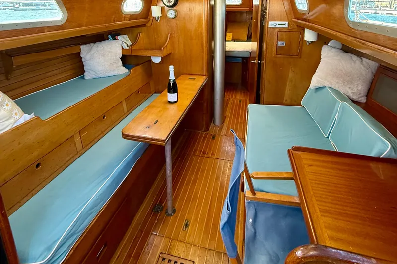 Slide: The Image of 1970 Hinckley 38 sailboat interior with wooden furnishings and blue cushions. - 30