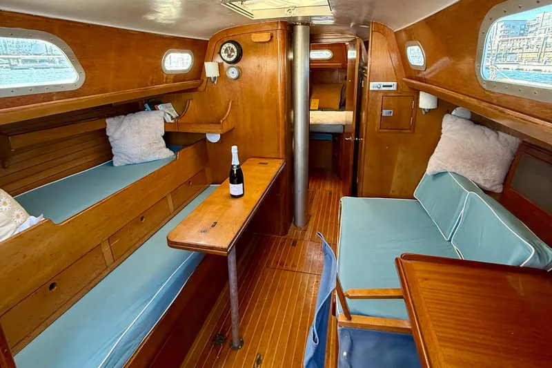 Slide: The Image of Interior of a 1970 Hinckley 38 sailboat with wooden furnishings and blue cushions. - 31