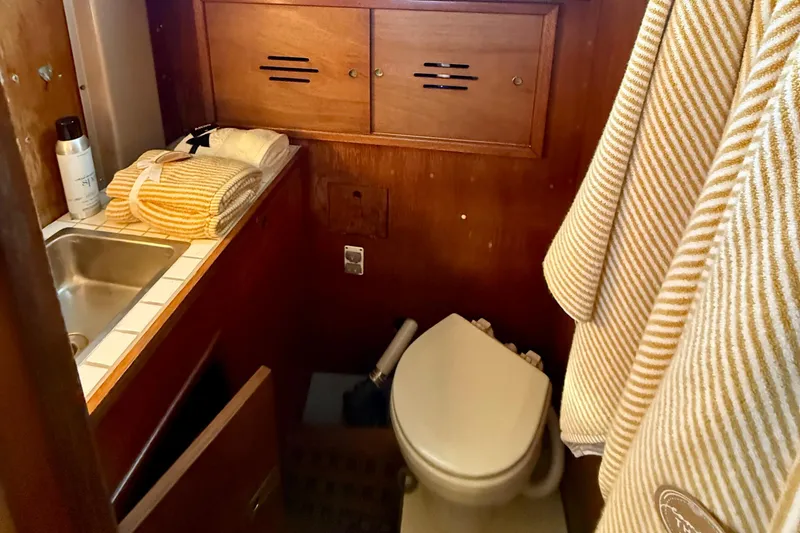 Slide: The Image of 1970 Hinckley 38 yacht bathroom with wooden cabinets, sink, and toilet. - 32