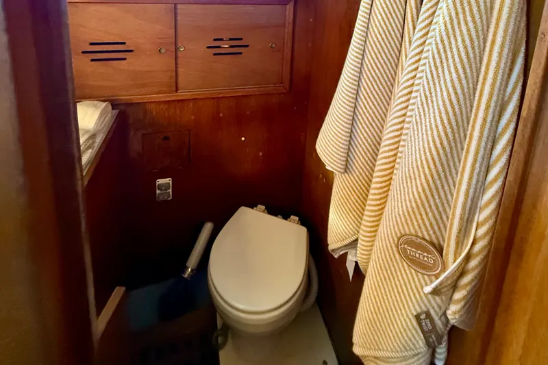 Slide: The Image of 1970 Hinckley 38 yacht bathroom with wooden cabinets and a compact toilet. - 33