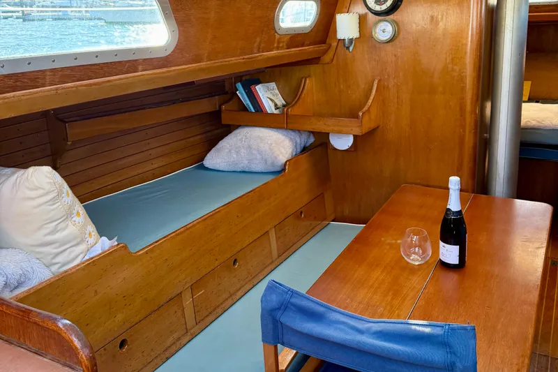 Slide: The Image of Interior of a 1970 Hinckley 38 sailboat with cozy wooden furnishings and a dining area. - 38
