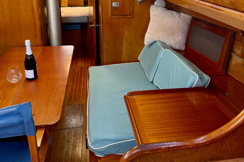Slide: The Image of Interior of a 1970 Hinckley 38 sailboat with wooden furnishings and a cozy seating area. - 39
