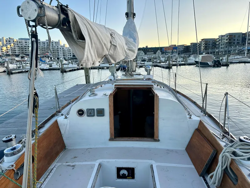 Slide: The Image of 1970 Hinckley 38 sailboat docked at marina during sunset, showcasing deck and cabin entrance. - 9