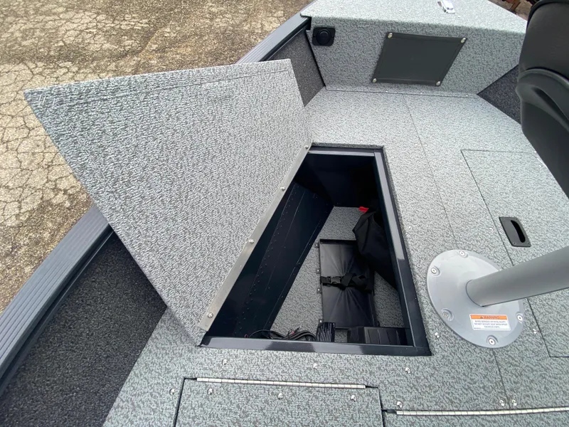 Slide: The Image of 2025 Lund 1650 Angler Tiller boat with open storage compartment, gray interior. - 10