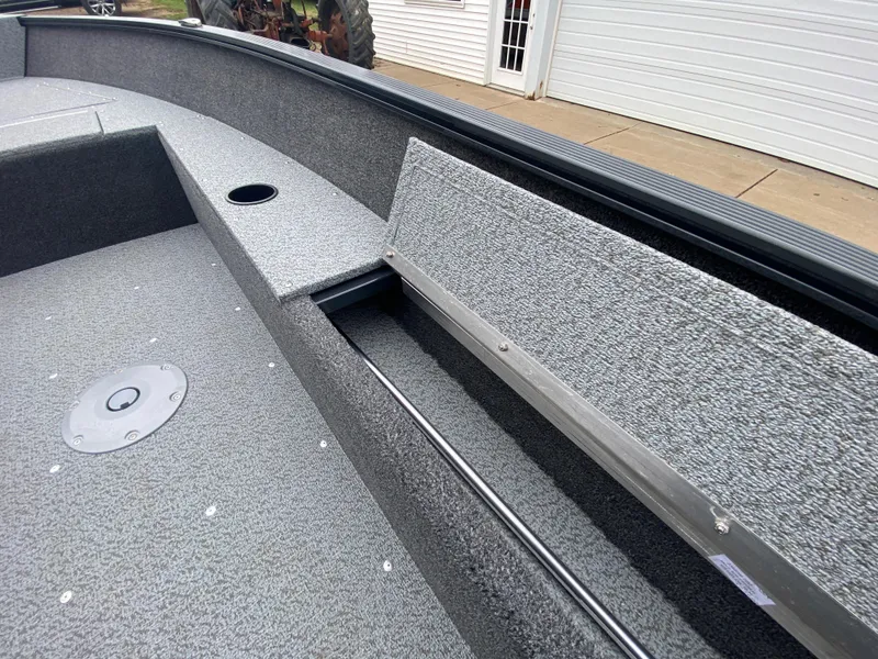 Slide: The Image of 2025 Lund 1650 Angler Tiller boat interior with textured flooring and storage compartment. - 16