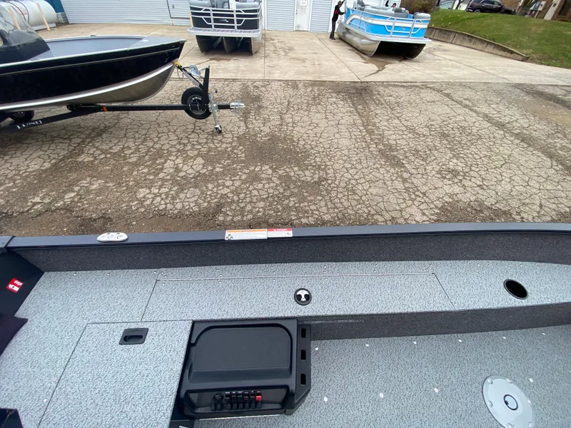 Slide: The Image of 2025 Lund 1650 Angler Tiller boat interior with trailer in background. - 17