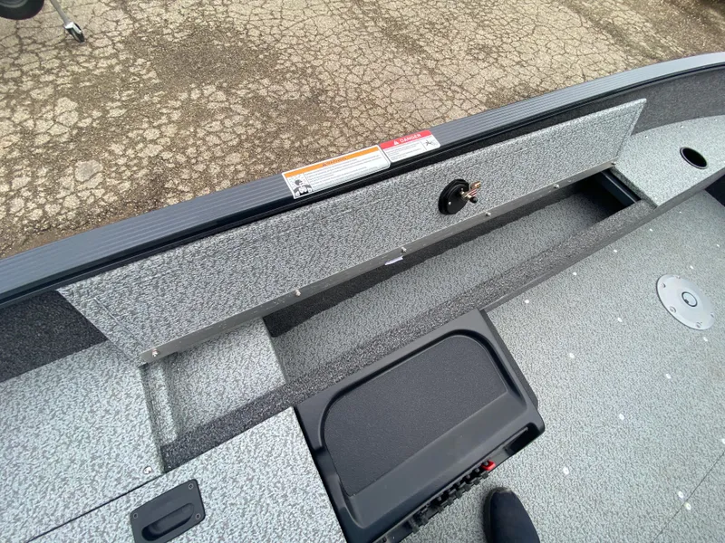 Slide: The Image of 2025 Lund 1650 Angler Tiller boat interior with storage compartment and textured flooring. - 18