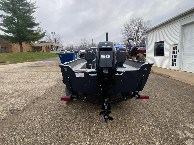 Slide: The Image of 2025 Lund 1650 Angler Tiller boat with Mercury 50 engine, parked outdoors. - 2