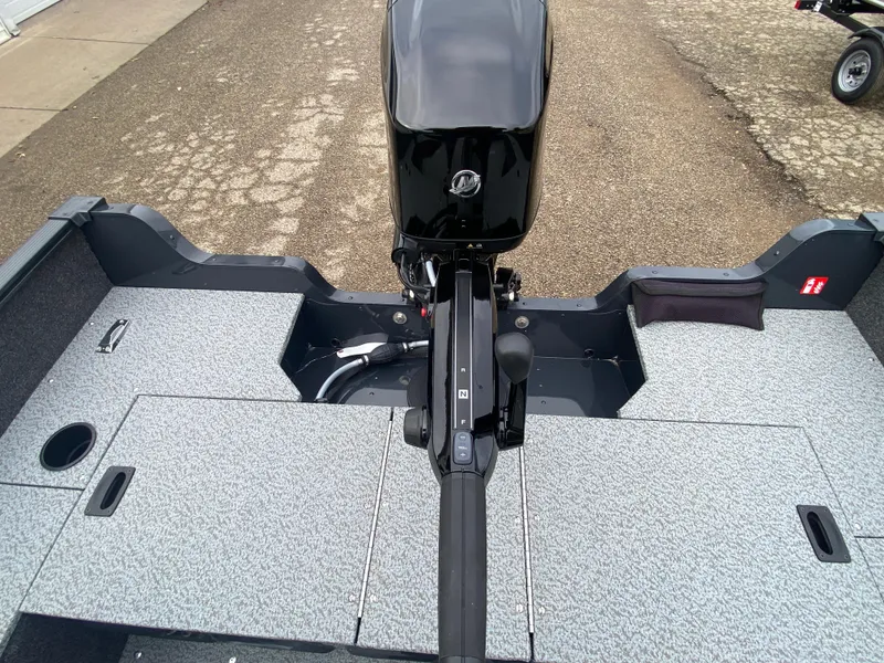 Slide: The Image of 2025 Lund 1650 Angler Tiller boat interior with motor, gray flooring, and storage compartments. - 26