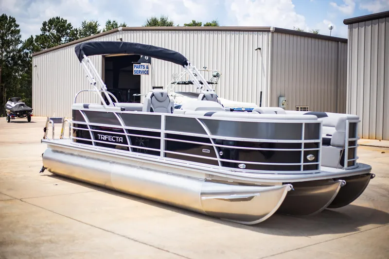 Slide: The Image of 2025 Trifecta 22RF LE2.75 pontoon boat parked outside service center. - 1
