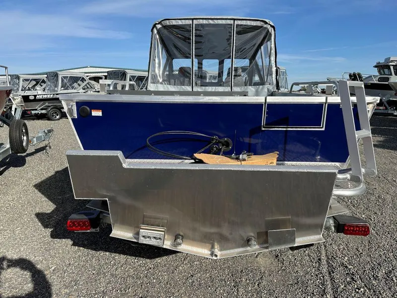 Slide: The Image of 2025 Hewescraft 210 Sea Runner ET boat, rear view, parked on gravel lot. - 3
