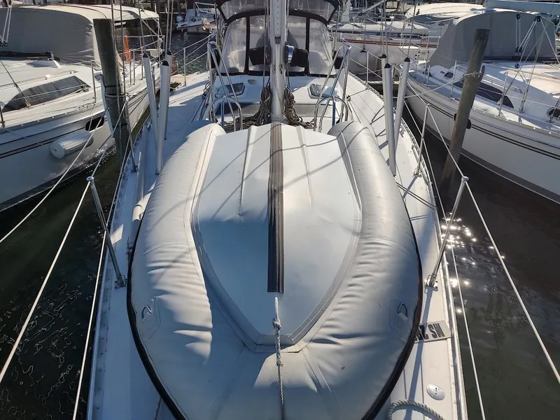 Slide: The Image of Sailboat docked at marina, featuring a 1997 Hylas 46 model with inflatable dinghy on deck. - 13