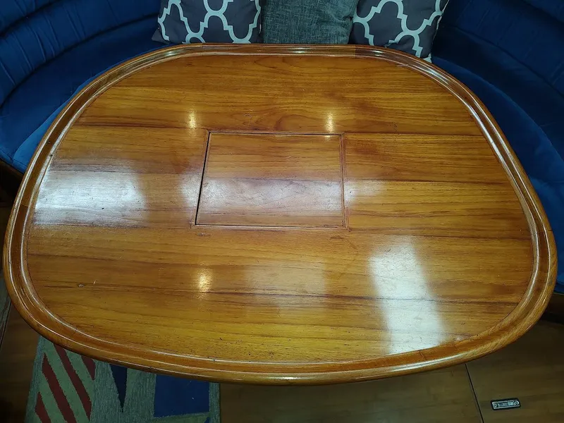 Slide: The Image of Wooden table on a Hylas 46 yacht, 1997 model, with blue seating and patterned cushions. - 31