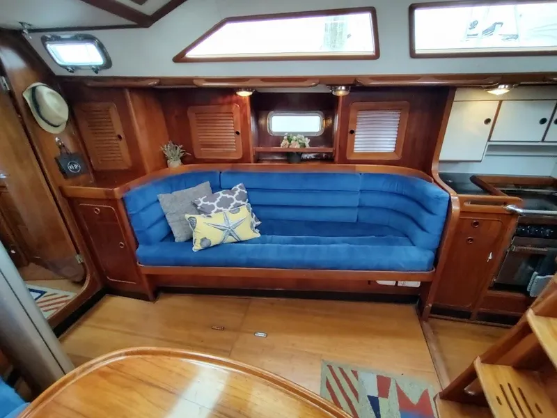 Slide: The Image of Interior of 1997 Hylas 46 yacht with blue cushioned seating and wooden cabinetry. - 33