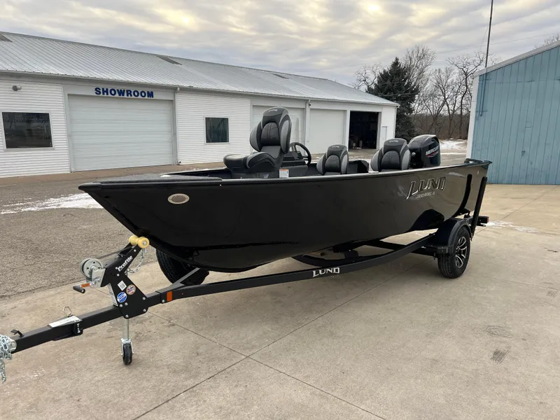 Slide: The Image of 2025 Lund 1650 Rebel XL SS Blackout boat on trailer outside showroom. - 2