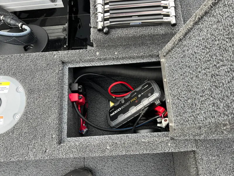 Slide: The Image of 2025 Lund 1650 Rebel XL SS Blackout boat storage compartment with battery charger and cables. - 21